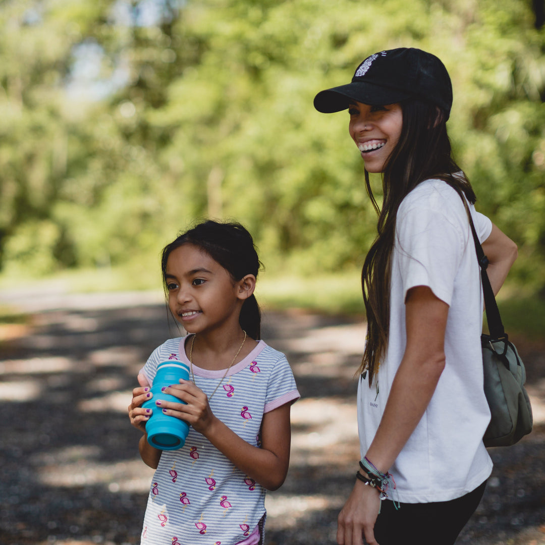 Woman and child walking outdoors with a blue HYDAWAY Collapsible water bottle