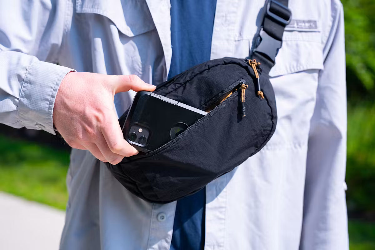 Traveler wearing the Pakt Stash Packable Sling while exploring outdoors, carrying everyday essentials in a lightweight, compact crossbody bag designed for travel and adventure.