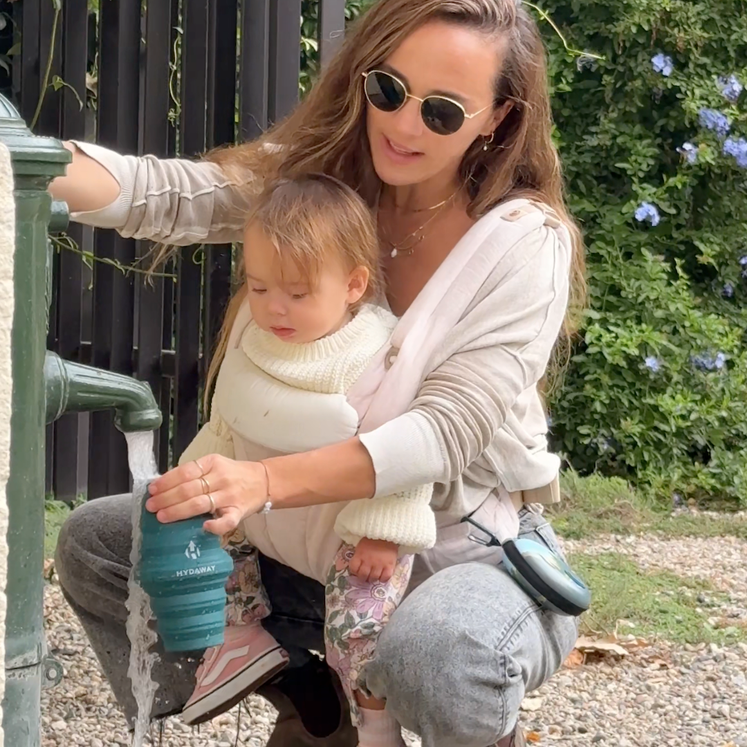 Woman and child at a water fountain with a HYDAWAY collapsible water bottle