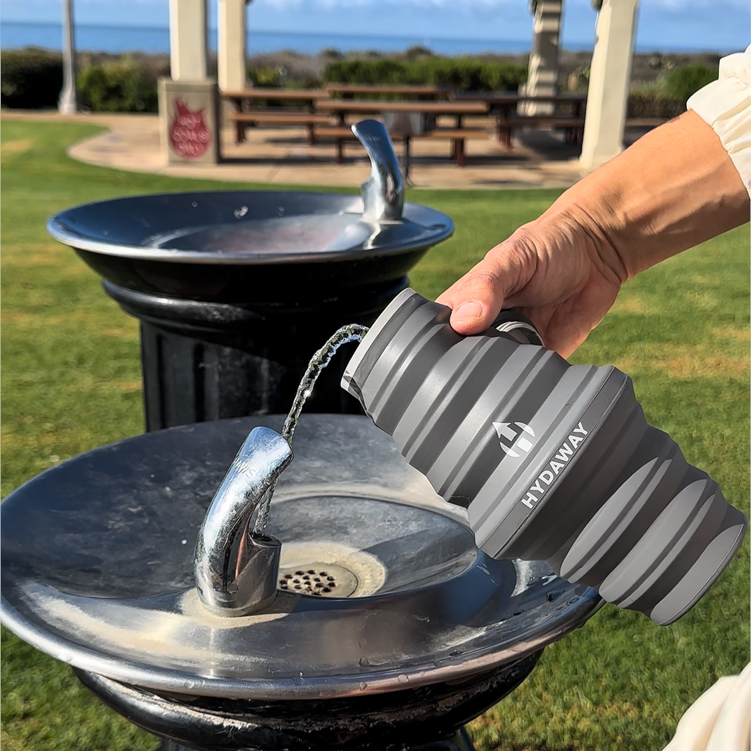 Person filling up a HYDAWAY collapsible water bottle at a water fountain